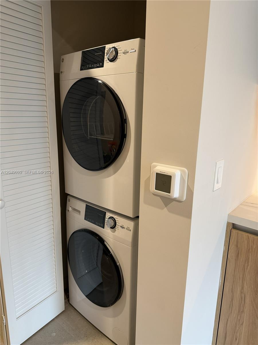 A stacked washer and dryer unit is located in a closet next to a thermostat — 11 NE 6th St # 515, Miami FL 33132, MIAMI, FL