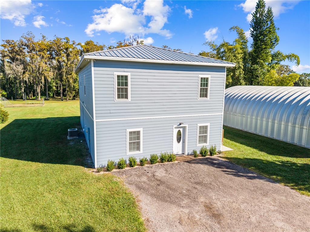 A two-story, light blue house with a metal roof stands on a grassy lot — 4055 EDSEL AVENUE, ST CLOUD, FL