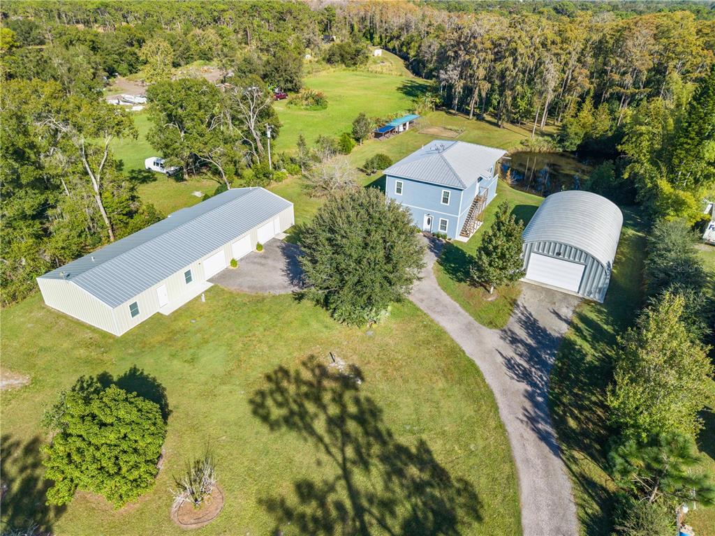 An aerial view shows a blue house, a large workshop, and a metal garage on a lot — 4055 EDSEL AVENUE, ST CLOUD, FL