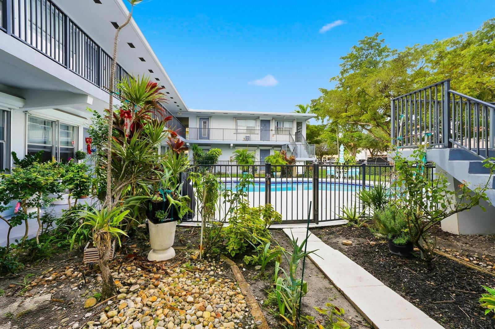 An outdoor courtyard features a swimming pool enclosed by a black metal fence and stairs — 3510 Harrison Street # 4, Hollywood FL 33021, HOLLYWOOD, FL