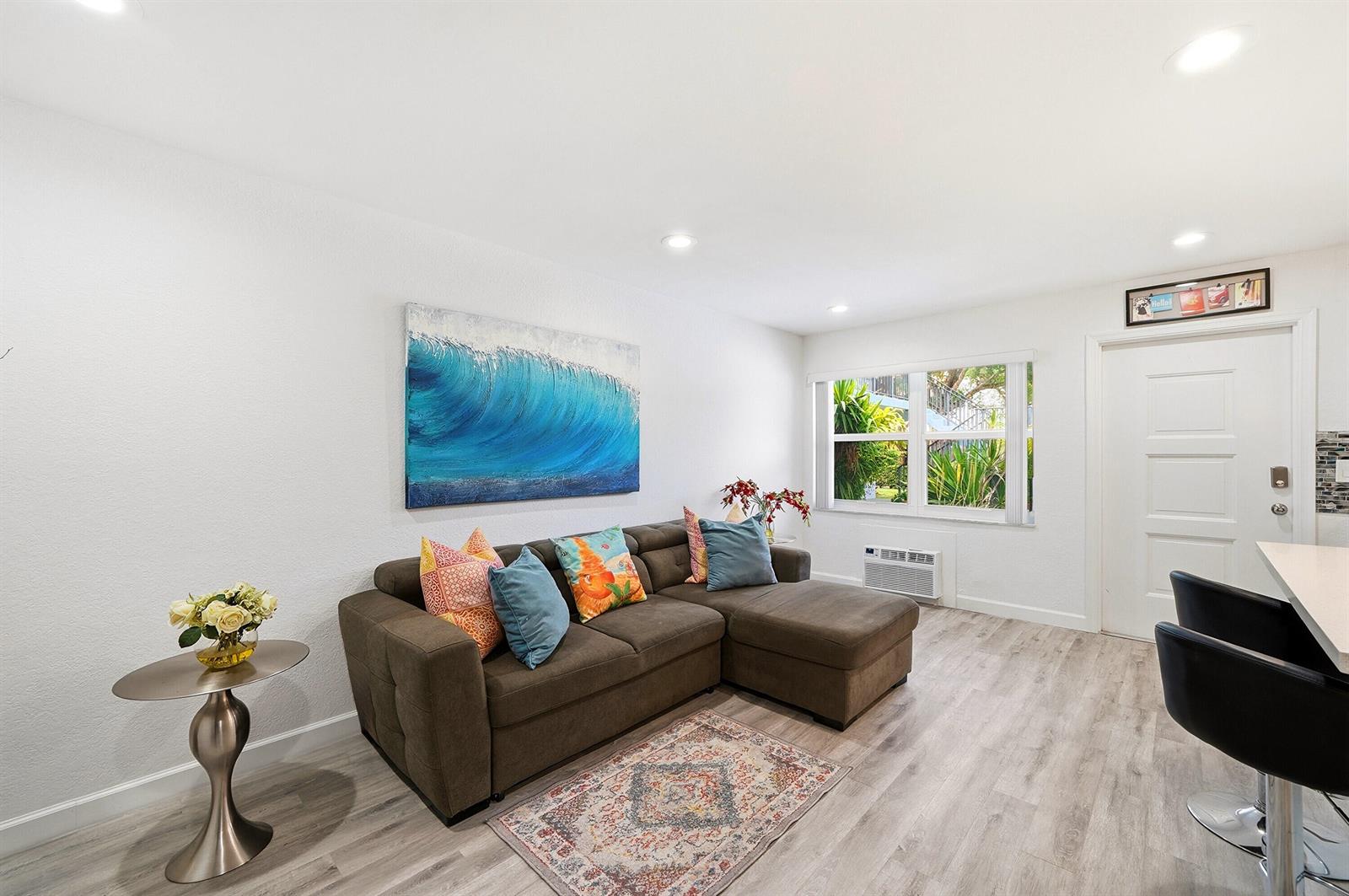 A living room features a brown sectional sofa, a wave painting, and light wood flooring — 3510 Harrison Street # 4, Hollywood FL 33021, HOLLYWOOD, FL