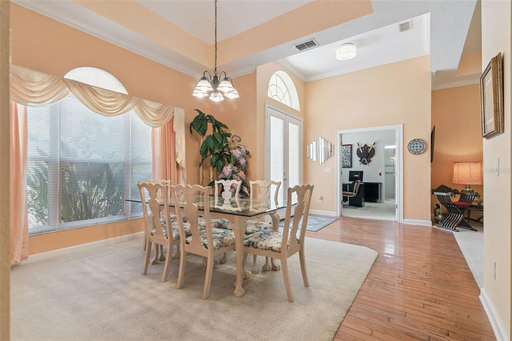 A dining room with a glass table, floral chairs, and a large window with drapes — 126 SEVILLE CHASE DRIVE, WINTER SPRINGS, FL