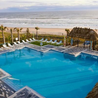 An outdoor swimming pool overlooks a sandy beach and the ocean — 1002 SEA SHELL COURT, DAYTONA BEACH, FL