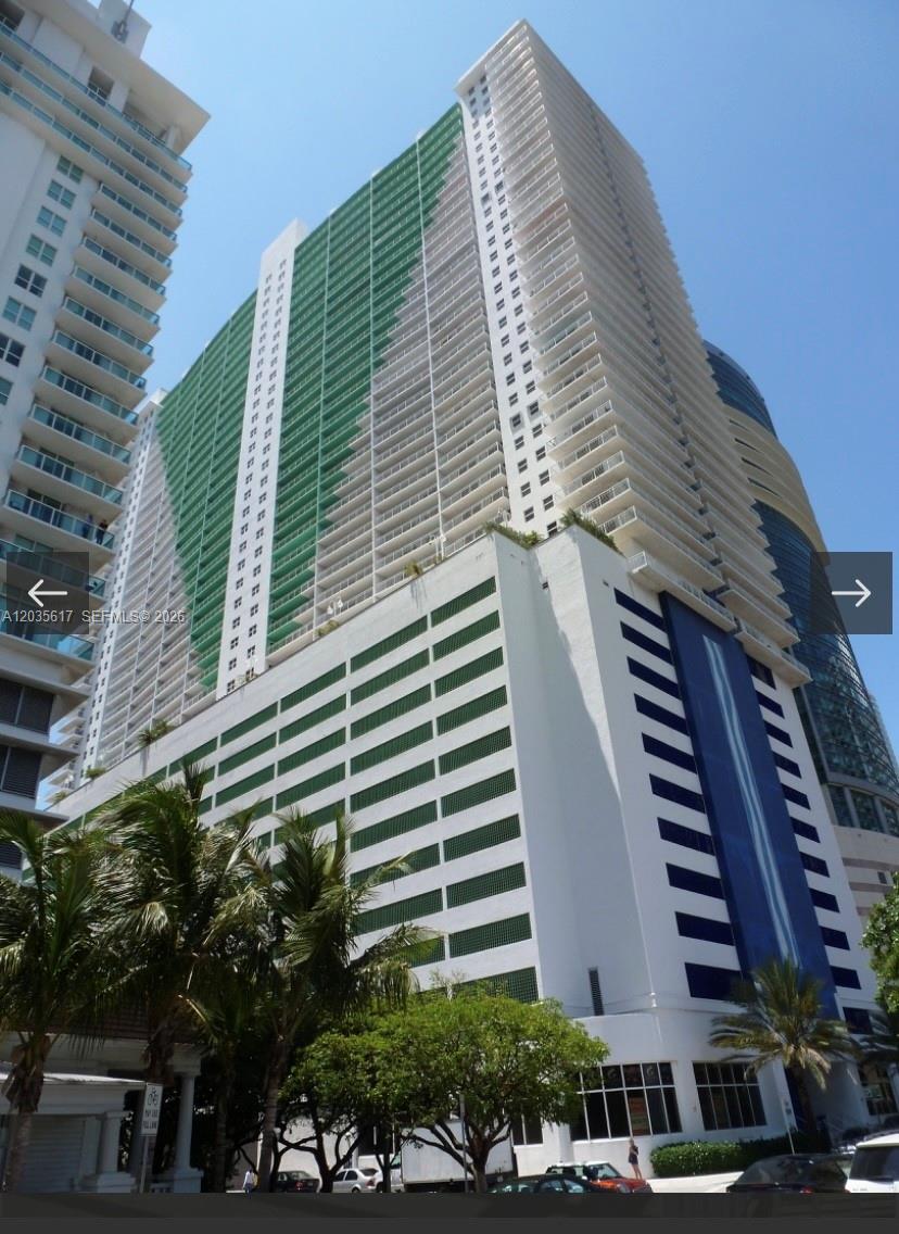 A low-angle view of a tall residential high-rise building with a green-accented parking garage base — 1200 Brickell Bay Dr # 3318, Miami FL 33131, MIAMI, FL