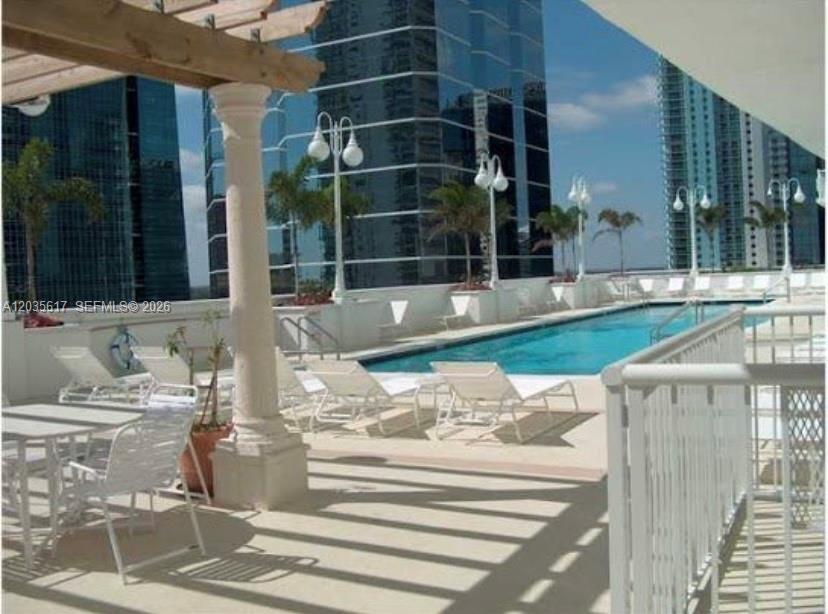 A swimming pool on a terrace with lounge chairs, a pergola, and surrounding high-rise buildings — 1200 Brickell Bay Dr # 3318, Miami FL 33131, MIAMI, FL