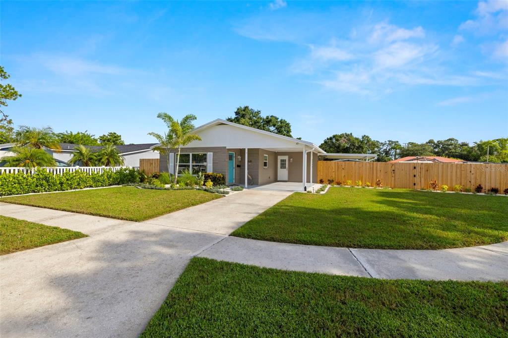 A single-story house with a gray facade, a covered carport, and a wooden privacy fence — 6545 S WEST SHORE CIRCLE, TAMPA, FL