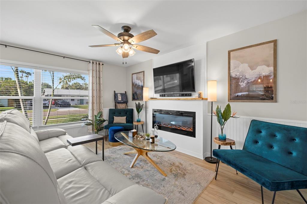 A living room features a grey sofa, a teal velvet chair, and a fireplace with television — 6545 S WEST SHORE CIRCLE, TAMPA, FL
