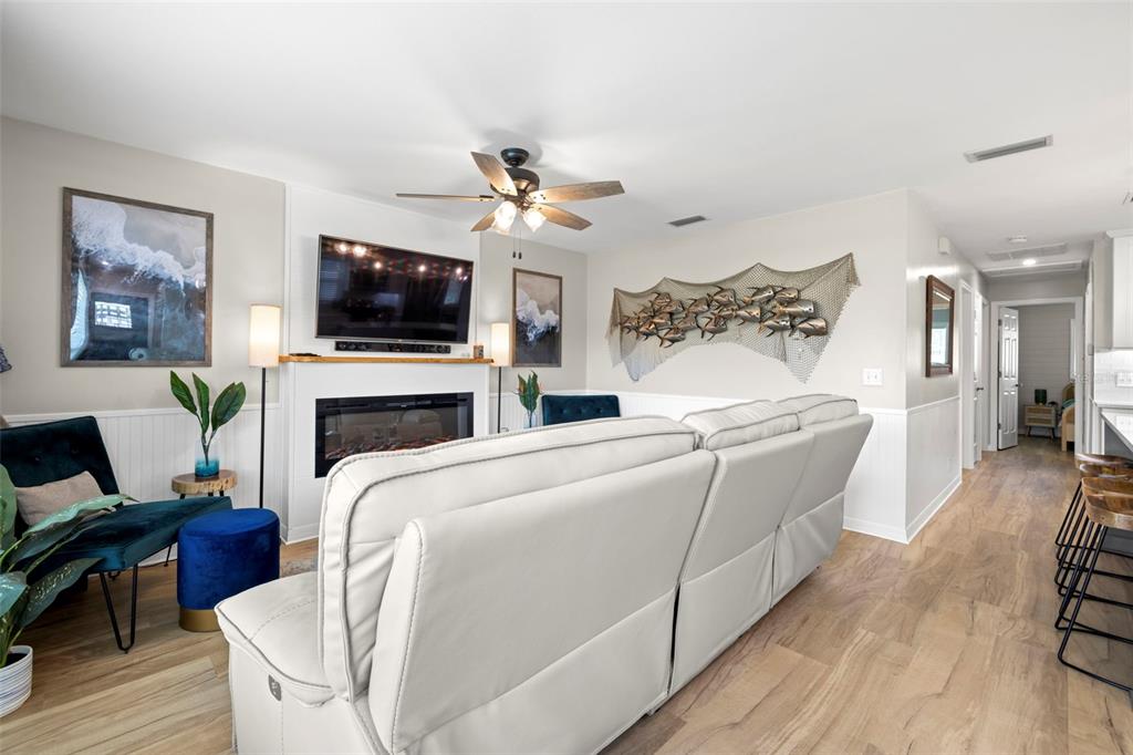 A living room features a white sofa, fireplace, television, and coastal-themed wall decor — 6545 S WEST SHORE CIRCLE, TAMPA, FL