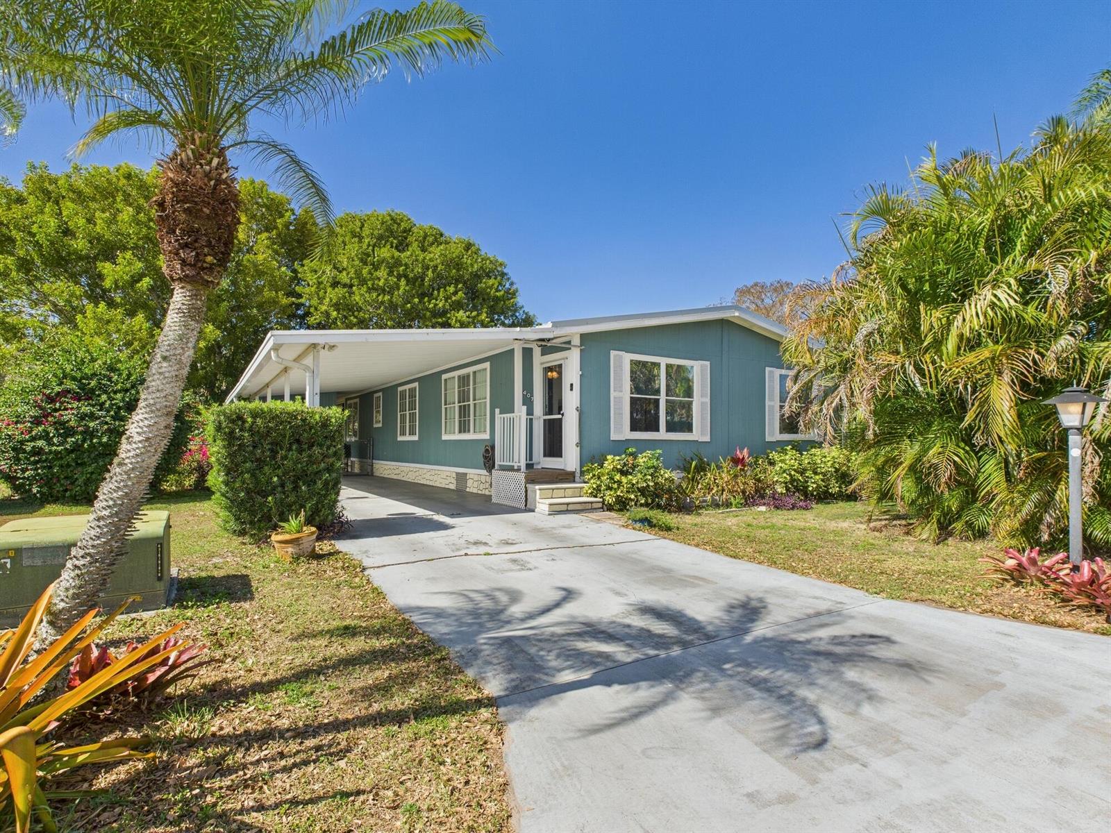 A blue mobile home with a carport, concrete driveway, and surrounding palm trees — 407 NE 8th Avenue, Okeechobee FL 34972, OKEECHOBEE, FL