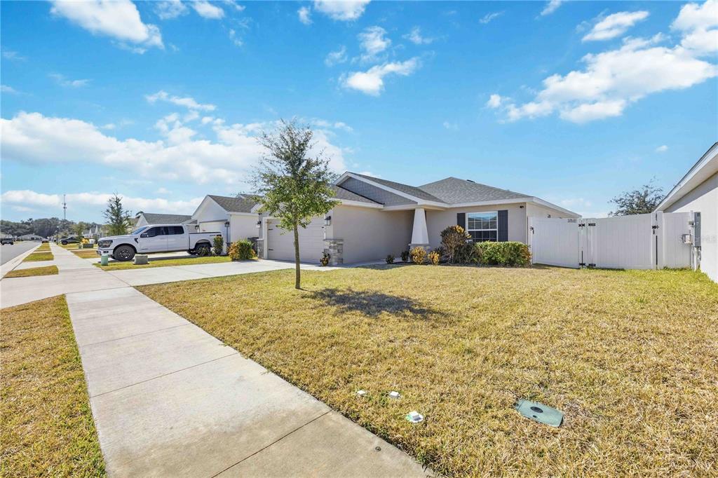 A single-story suburban house with a tan exterior, a concrete driveway, and a white fence — 1035 TROPEA LANE, AUBURNDALE, FL