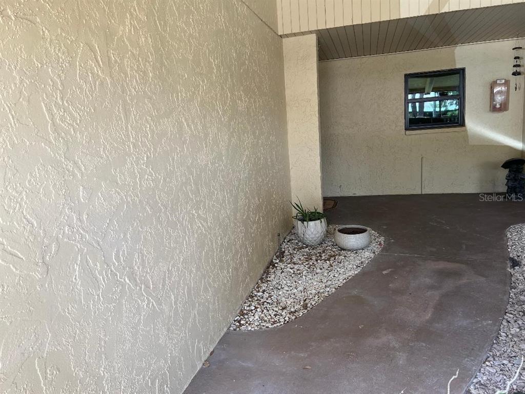 A covered entryway features a textured stucco wall, a concrete floor, and a gravel garden — 1220 13TH CIRCLE SE, LARGO, FL