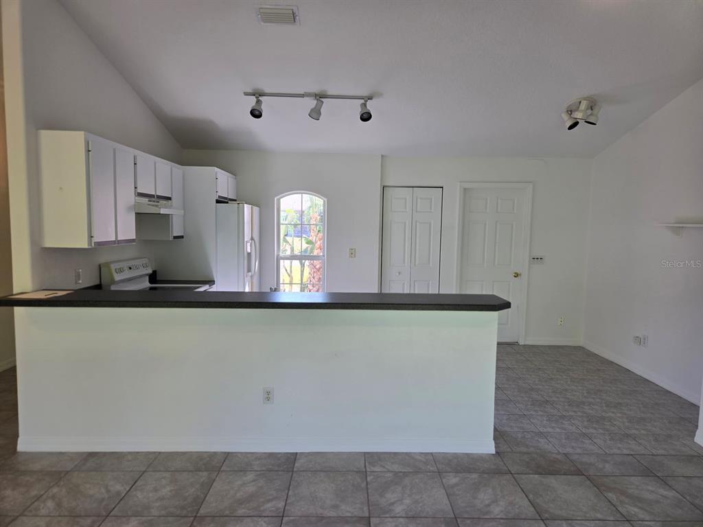 A kitchen with white cabinets, a dark countertop, and tile flooring overlooks an adjacent room — 2338 FERN PALM DRIVE, EDGEWATER, FL