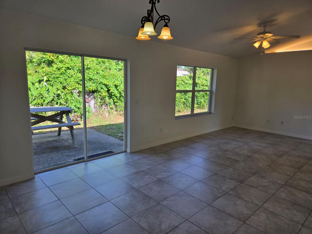 An interior room with tiled flooring, a ceiling fan, a chandelier, and a sliding door — 2338 FERN PALM DRIVE, EDGEWATER, FL