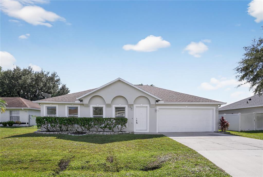 A single-story house with a white stucco exterior, arched window accents, and an attached garage — 1118 PERPIGNAN COURT, KISSIMMEE, FL