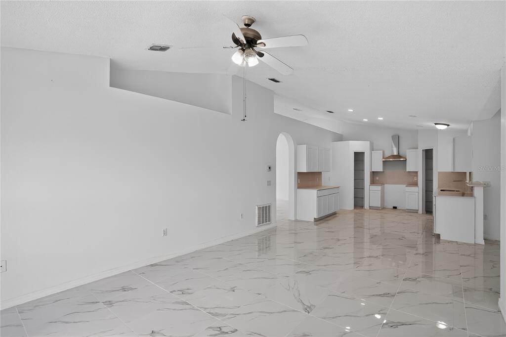 An empty room features white walls, a light fixture, and white marble-patterned tile flooring — 1118 PERPIGNAN COURT, KISSIMMEE, FL