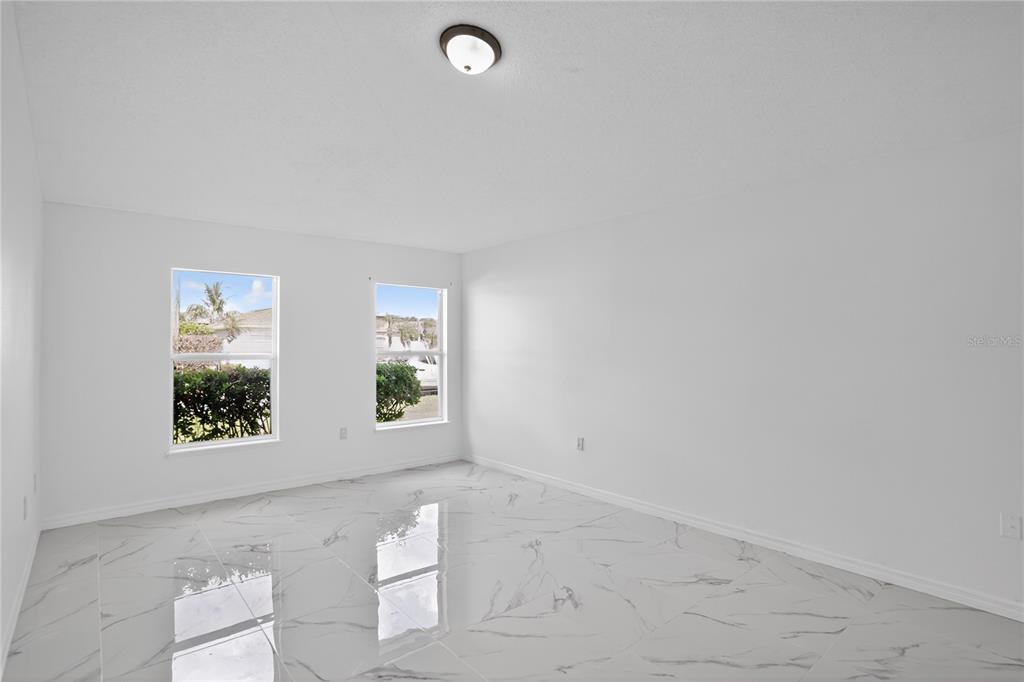 An empty room with white walls, vaulted ceilings, and glossy white marble-patterned tile flooring — 1118 PERPIGNAN COURT, KISSIMMEE, FL