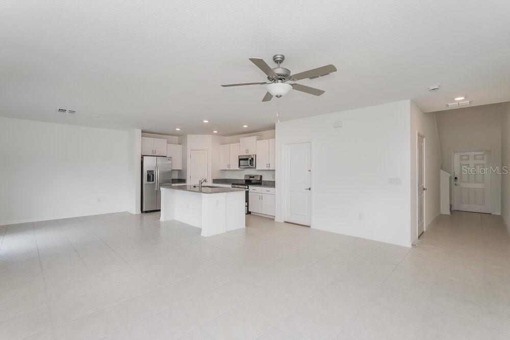 An open-concept kitchen with white cabinets, a center island, and tile flooring — 17895 BLISSFUL STARS DRIVE, LUTZ, FL