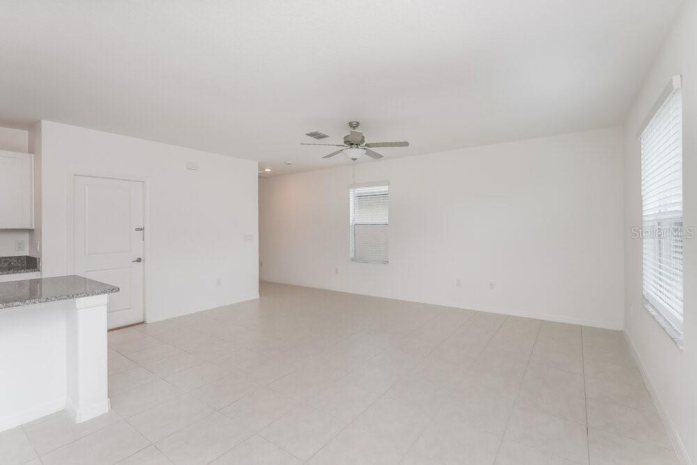 An open-concept living area features white walls, tile flooring, and a ceiling fan — 17895 BLISSFUL STARS DRIVE, LUTZ, FL
