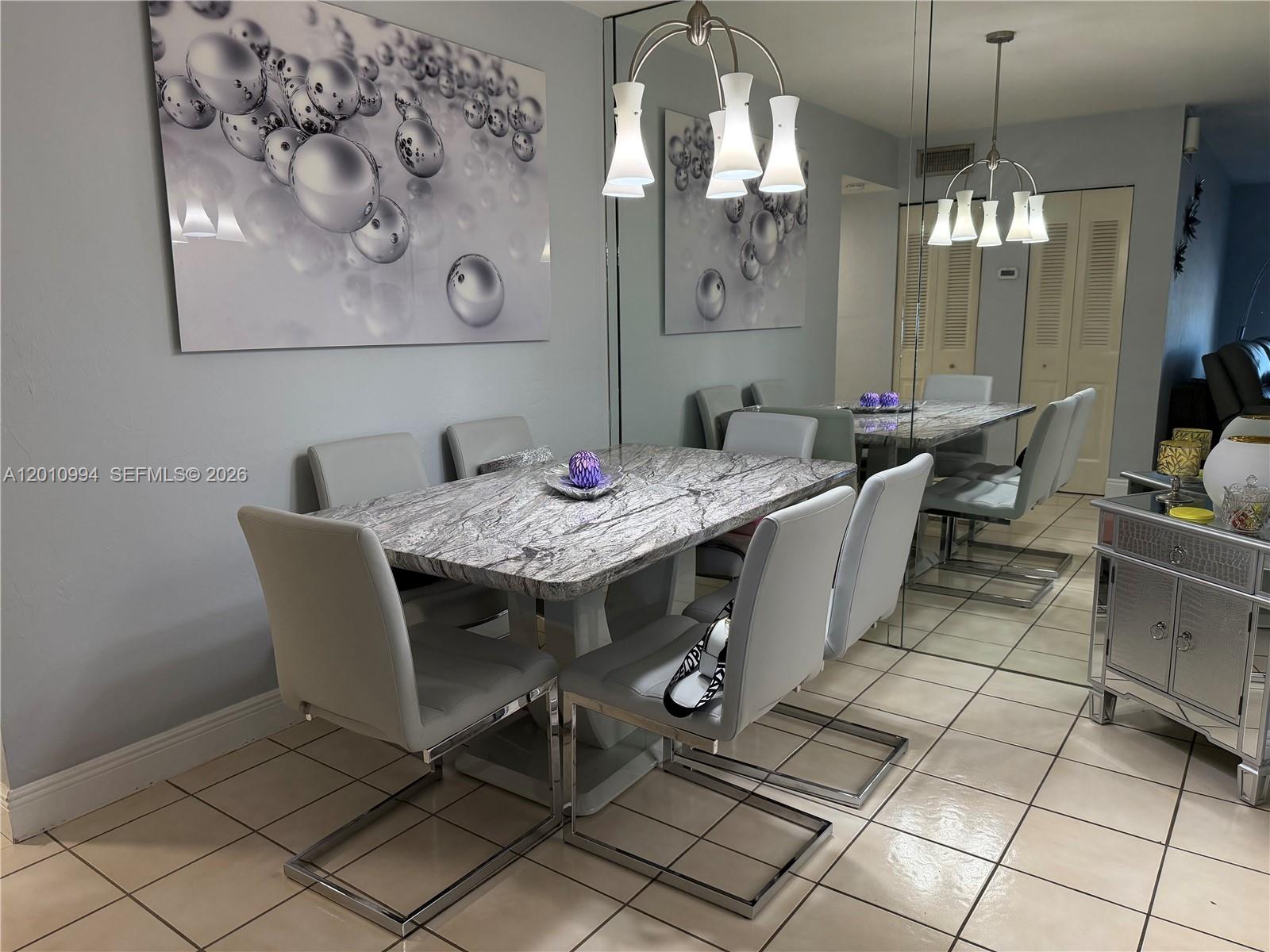A dining room features a marble-topped table, modern chairs, a mirrored wall, and pendant lighting — 7847 Miller Dr # A205, Miami FL 33155, MIAMI, FL