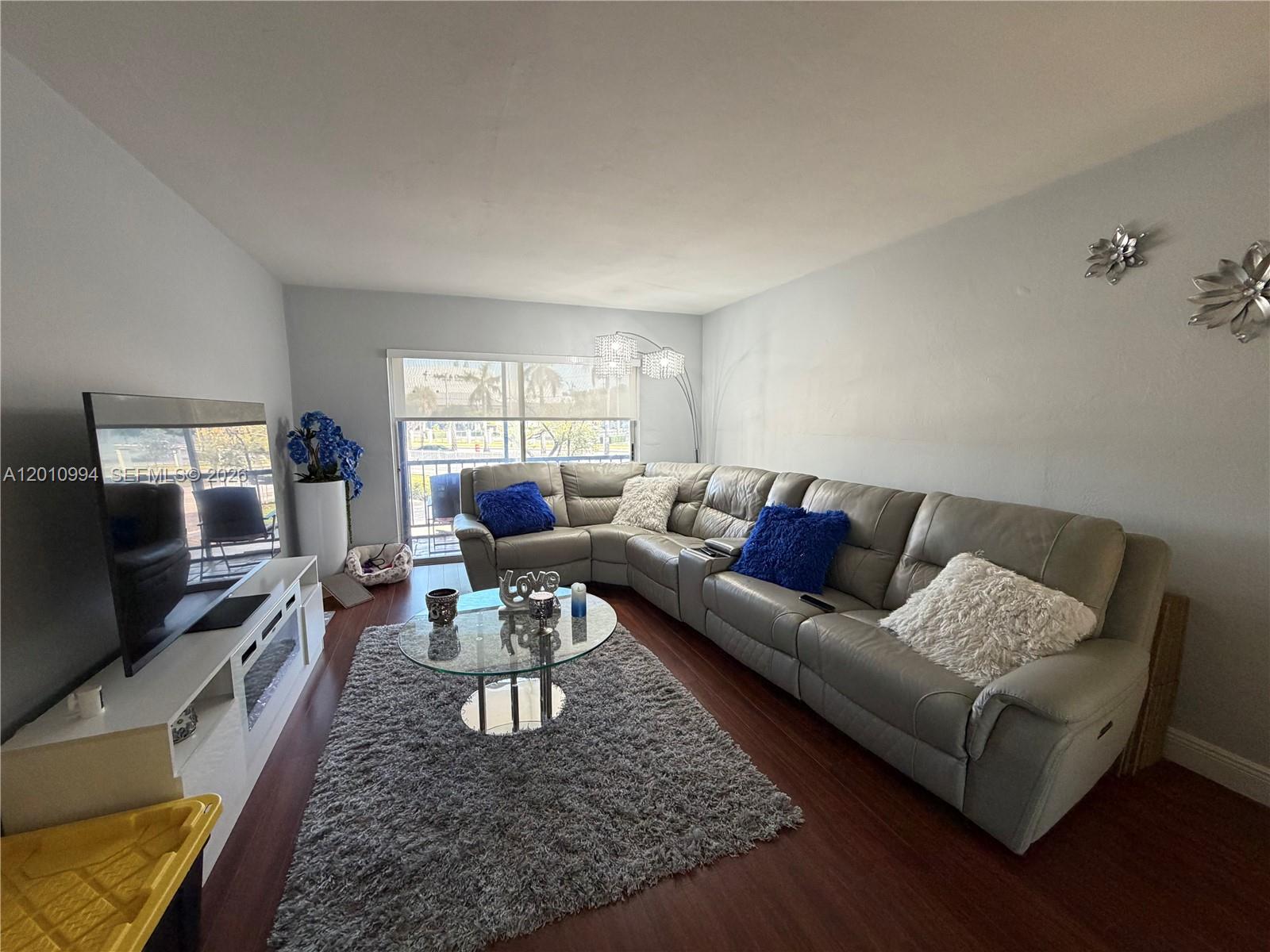 A living room features a grey sectional sofa, a glass coffee table, and a television — 7847 Miller Dr # A205, Miami FL 33155, MIAMI, FL
