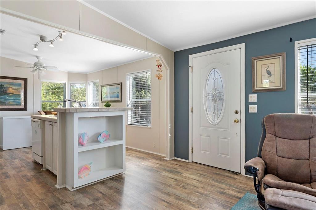 A living room with wood-look flooring, a kitchen island, and a white front door — 3101 BAMBOO COURT, PUNTA GORDA, FL