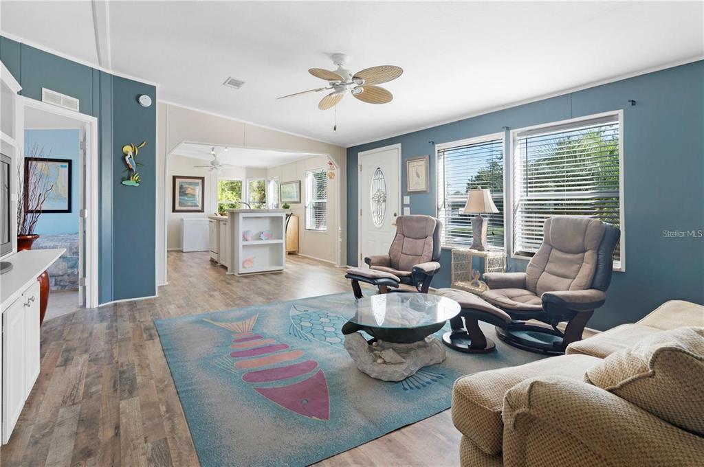 A living room features blue walls, wood-look flooring, a fish-patterned rug, and two reclining chairs — 3101 BAMBOO COURT, PUNTA GORDA, FL