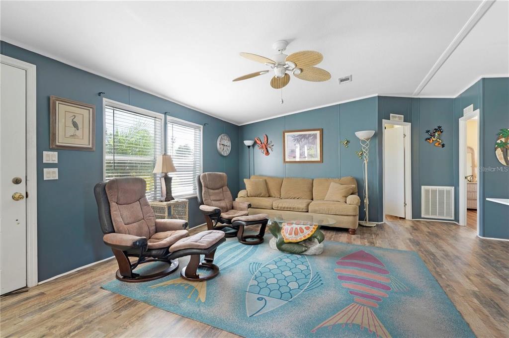 A living room features blue walls, a fish-patterned area rug, and a tan sofa — 3101 BAMBOO COURT, PUNTA GORDA, FL