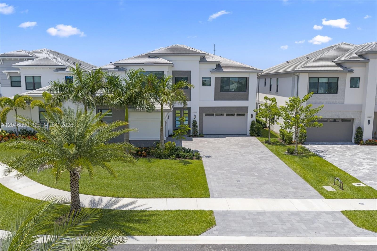 A two-story suburban house features a paved driveway, a two-car garage, and palm trees — 12866 Crane Xing, Palm Beach Gardens FL 33412, PALM BEACH GARDENS, FL