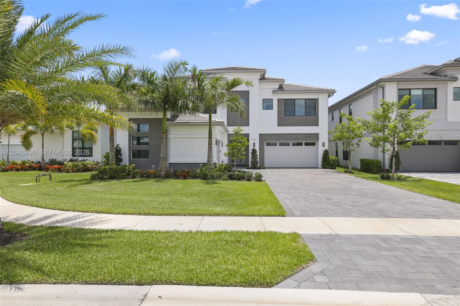 A two-story modern house features a paved driveway, a two-car garage, and palm trees — 12866 Crane Xing, Palm Beach Gardens FL 33412, PALM BEACH GARDENS, FL