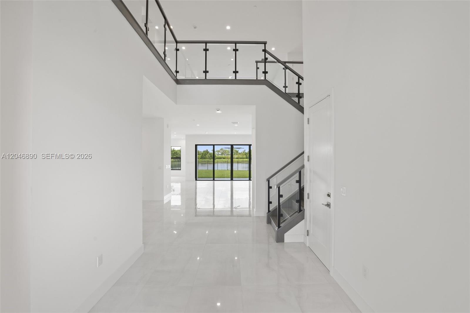 A bright, modern entryway features white tile floors, a glass-railed staircase, and a rear view — 12866 Crane Xing, Palm Beach Gardens FL 33412, PALM BEACH GARDENS, FL