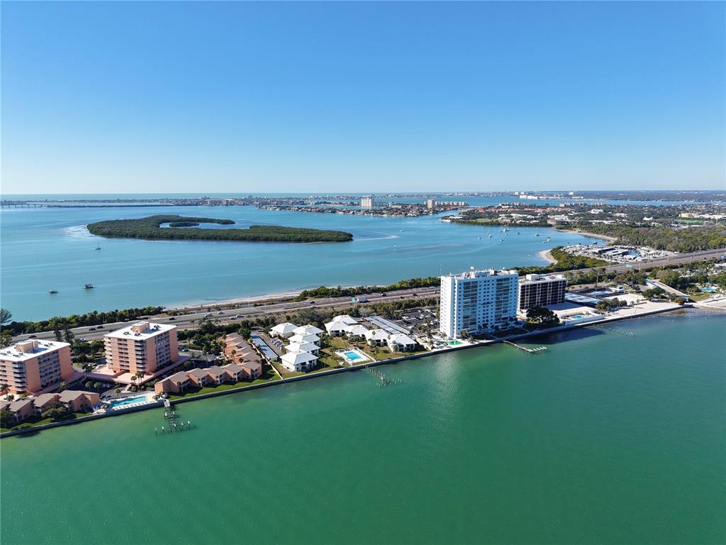 An aerial view shows a coastal residential complex with multiple buildings along a waterfront — 7310 SUNSHINE SKYWAY LANE S UNIT 112, ST PETERSBURG, FL