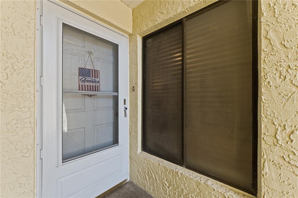 A white storm door and a large sliding window are set into a textured wall — 7310 SUNSHINE SKYWAY LANE S UNIT 112, ST PETERSBURG, FL