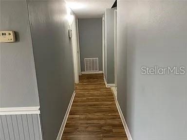 A hallway with gray walls, white trim, and wood-look flooring leads to a back room — 1695 LEE ROAD UNIT C103, WINTER PARK, FL