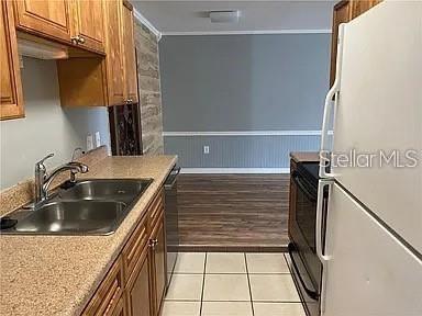 A kitchen features light wood cabinets, a double sink, and a white refrigerator — 1695 LEE ROAD UNIT C103, WINTER PARK, FL