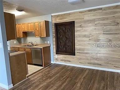 A kitchen with wood cabinets and a wood-paneled accent wall featuring a decorative metal insert — 1695 LEE ROAD UNIT C103, WINTER PARK, FL