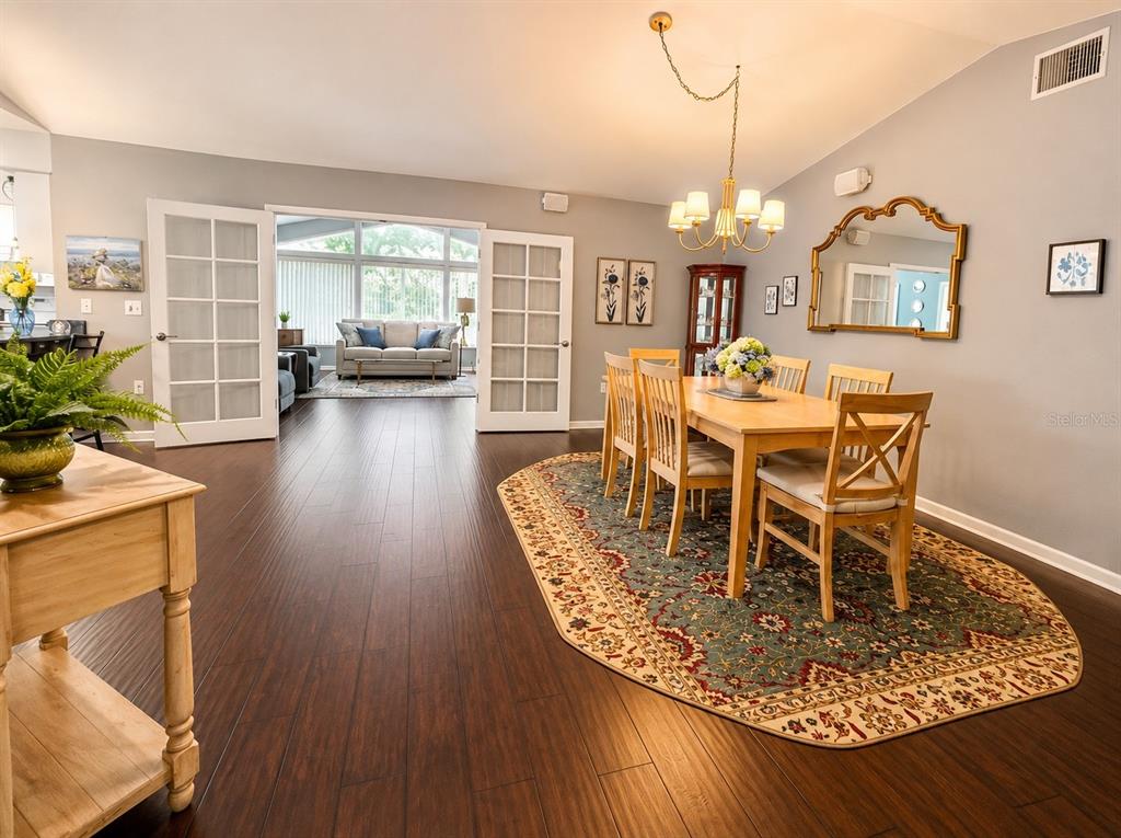 A dining room with dark wood floors, a wooden table, and French doors leading outside — 2228 GRAND CYPRESS DRIVE, LAKELAND, FL