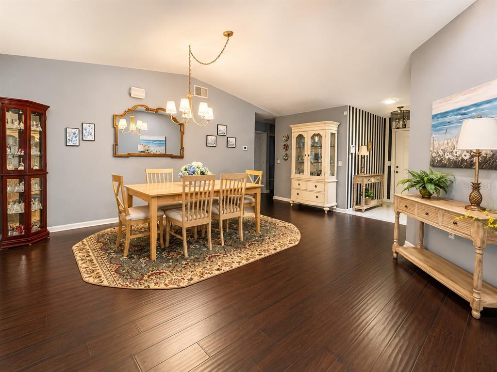 A dining room with a wooden table, oval rug, hutch, and console table on hardwood floors — 2228 GRAND CYPRESS DRIVE, LAKELAND, FL