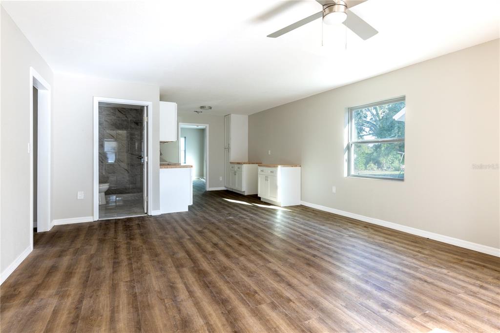 A spacious room with wood-look flooring, white cabinets, and a view into a tiled bathroom — 1740 2ND STREET NE, WINTER HAVEN, FL