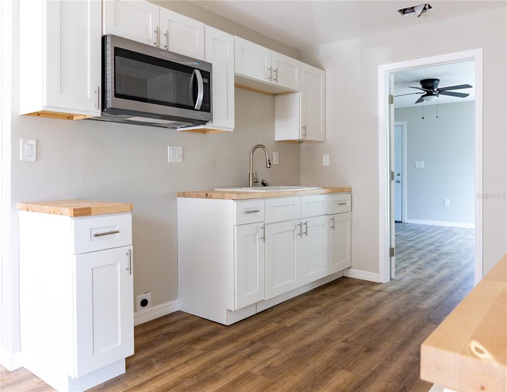 A kitchen features white cabinets, a stainless steel microwave, and light wood countertops — 1740 2ND STREET NE, WINTER HAVEN, FL