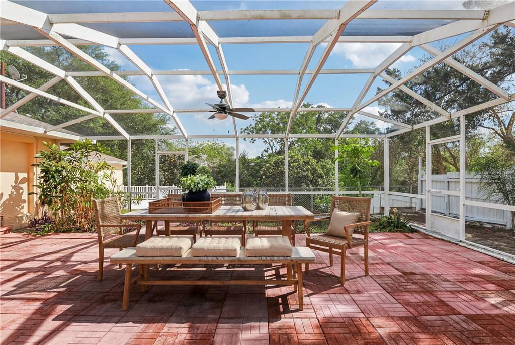 A screened-in patio features a dining table, chairs, and a bench on a brick floor — 1576 OHIO AVENUE, PALM HARBOR, FL