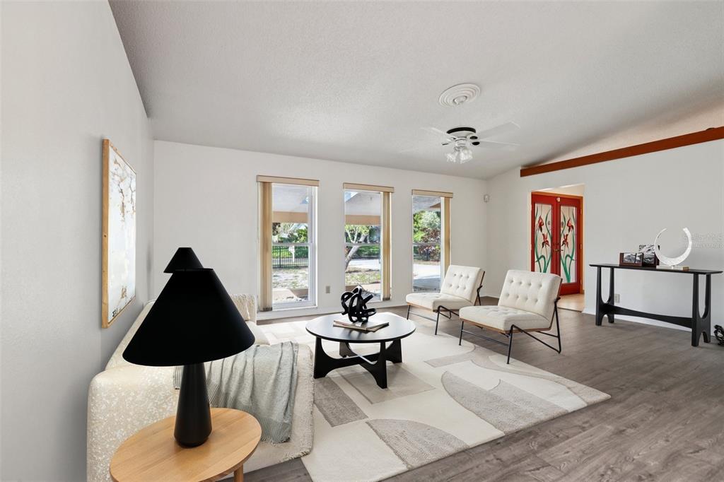 A living room features white walls, wood-look flooring, a patterned rug, and three tall windows — 1576 OHIO AVENUE, PALM HARBOR, FL