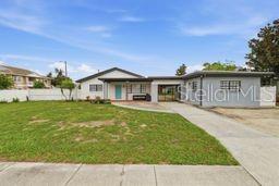 A single-story house with a light-colored exterior, a blue front door, and a concrete driveway — 2607 W CREST AVENUE, TAMPA, FL