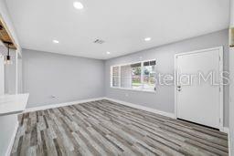 A bright, empty room features light gray walls, recessed lighting, and wood-look vinyl plank flooring — 2607 W CREST AVENUE, TAMPA, FL