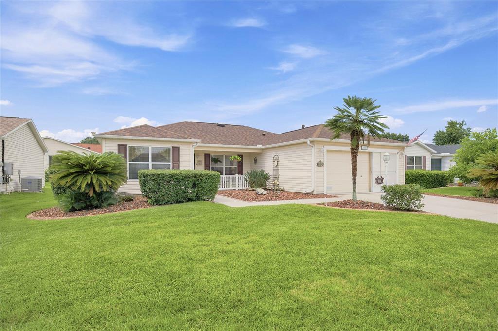 A single-story house with beige siding, a two-car garage, and a manicured front lawn — 3455 SIPSEY STREET, THE VILLAGES, FL