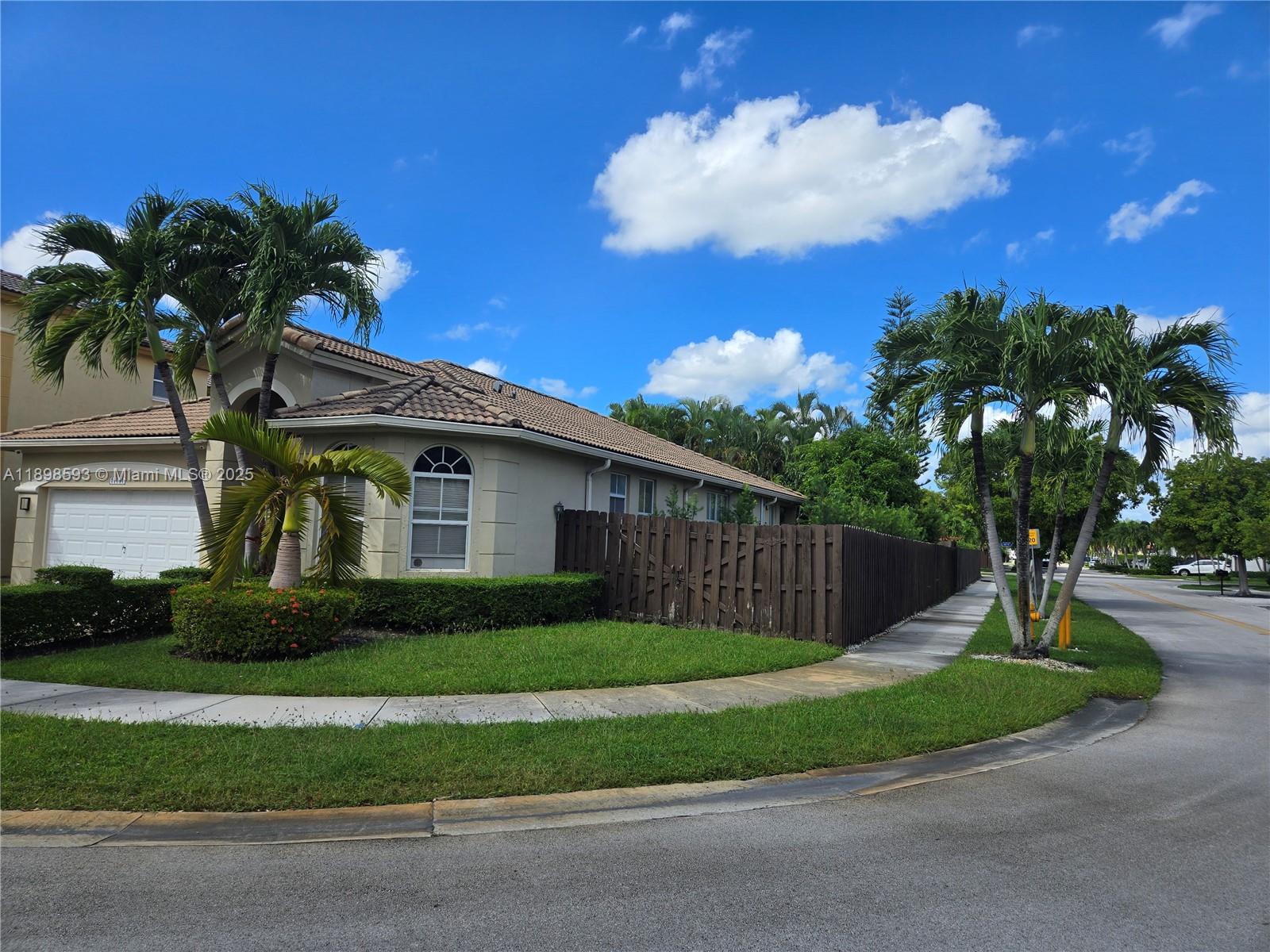 A single-story house with a tile roof, wooden fence, and palm trees on a corner lot — 11141 NW 77th Ter, Doral FL 33178, DORAL, FL