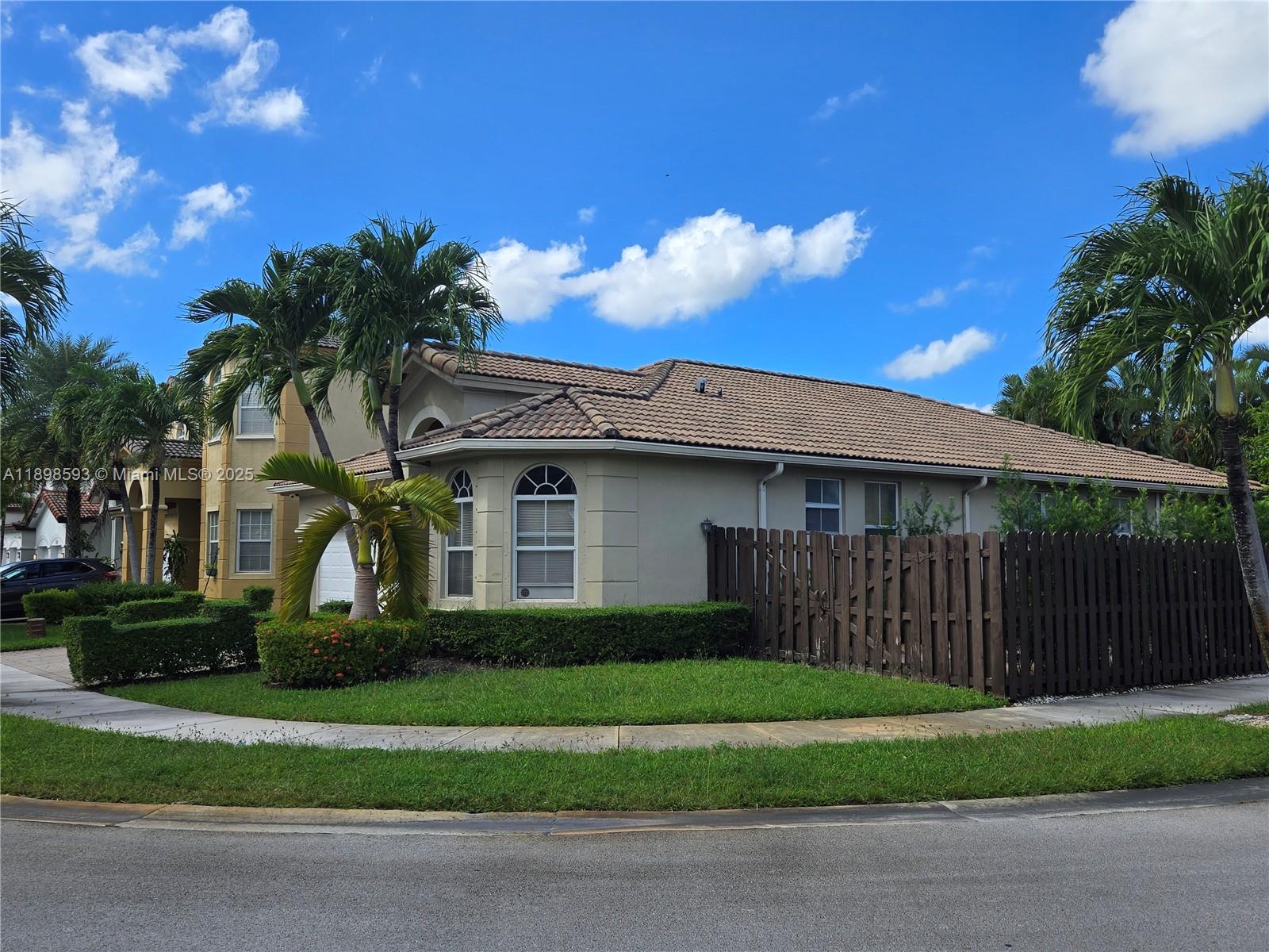 A beige single-story house with a tiled roof and a wooden fence sits outdoors — 11141 NW 77th Ter, Doral FL 33178, DORAL, FL