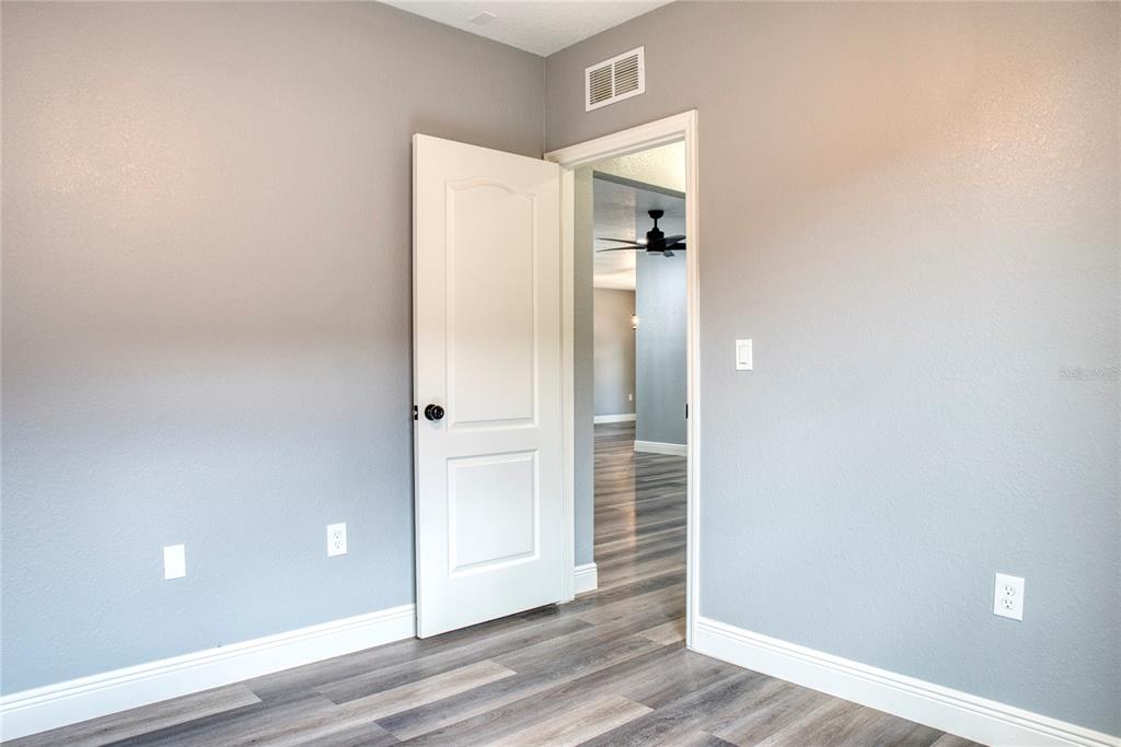 A room with gray walls, white trim, and wood-look flooring featuring an open doorway — 3711 JULIUS ESTATES BOULEVARD, WINTER HAVEN, FL