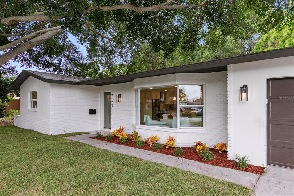 A white brick house exterior features a bay window, a green front door, and landscaping — 6795 14TH STREET S, ST PETERSBURG, FL