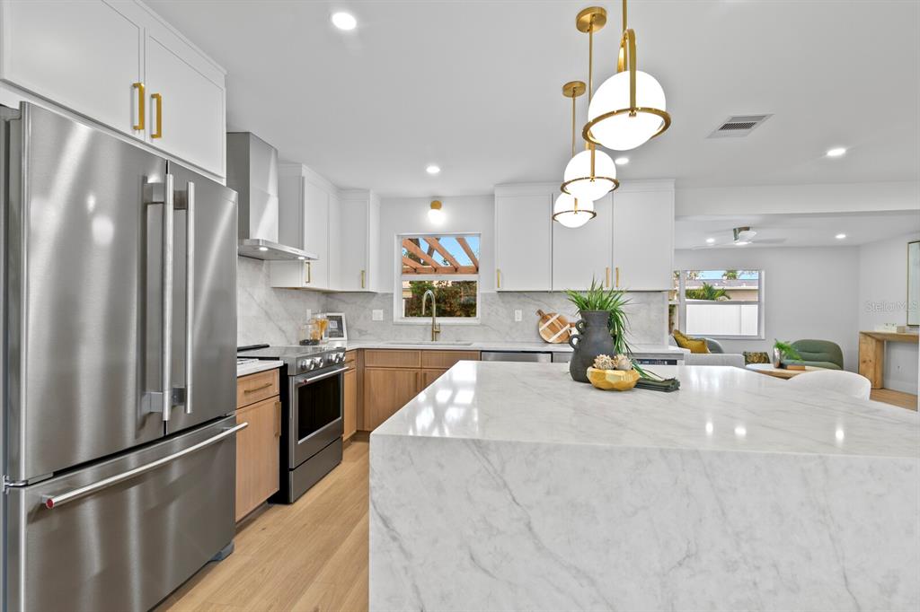A modern kitchen features a marble-topped island, stainless steel appliances, and two-toned cabinetry — 6795 14TH STREET S, ST PETERSBURG, FL