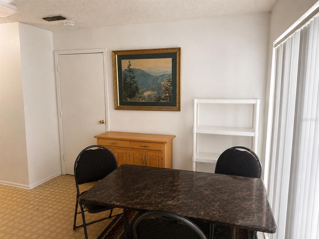 A dining area features a dark stone-topped table, black chairs, a wooden sideboard, and shelving — 8803 PARLIAMENT COURT, KISSIMMEE, FL